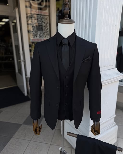 Black three-piece suit with a black shirt and tie